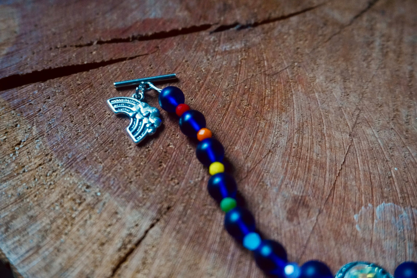 Bracelet with colorful beads and a silver charm on a wooden surface